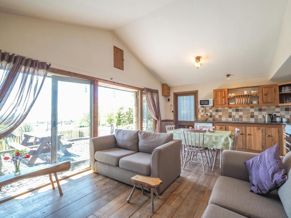 Living area with sofas, doors to garden, kitchen and dining area