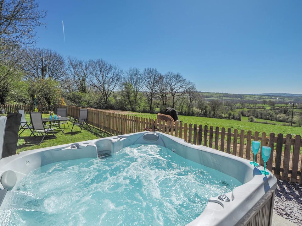 Hot tub with two wine glasses on the side, view of fields