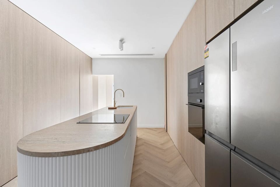 Sleek modern kitchen with high-end appliances, stylish wood finishes, and a spacious island—perfect for cooking and entertaining! By Superhostly