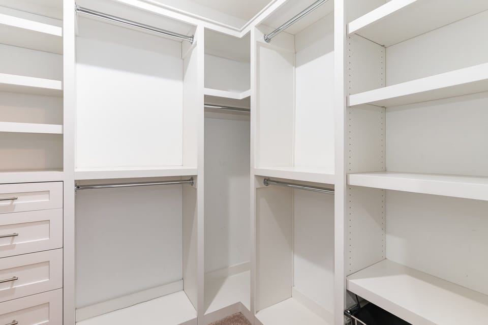 Unit 1: Primary Bathroom featuring a dual vanity with a stand-in shower, shower/tub combo, and walk-in closet.