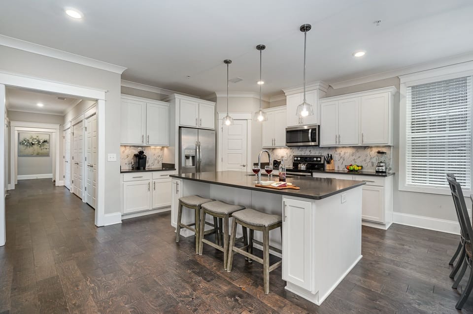 Unit 2: Fully equipped kitchen stocked with all culinary essentials, stainless steel appliances, and an island offering bar seating for 3 guests.