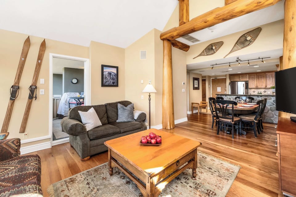 - Cozy living room with rustic wooden touches and warm natural sunlight  
- Relax after adventure-filled days surrounded by mountain-style decor  
- Open layout flows toward kitchen and dining, perfect for family moments 