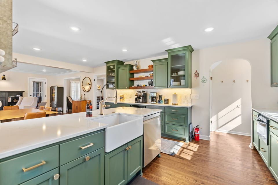 Your spacious kitchen features sage green cabinets, quartz countertops, and modern appliances perfect for preparing memorable meals during your stay.