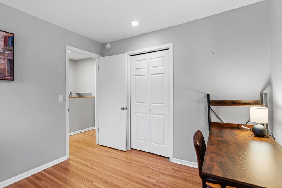 Your private workspace awaits with a rustic wooden desk, cozy lighting, and ample closet storage for all your belongings.