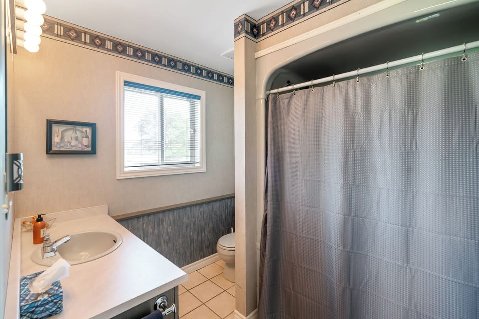 Main level bathroom w/ shower/tub, sink, towels, soaps, toilet paper, hairdryer