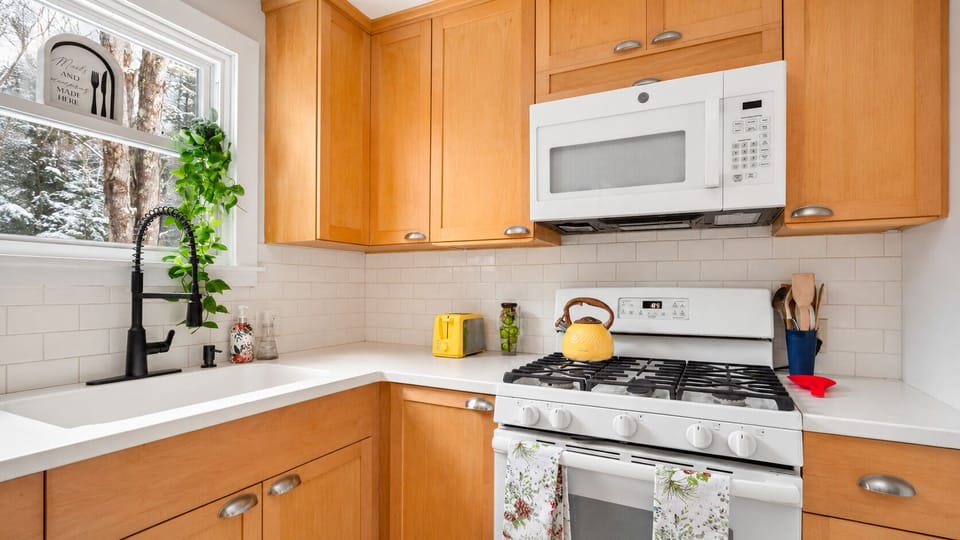 Bright kitchen with gas range, kettle on, ready for morning coffee.