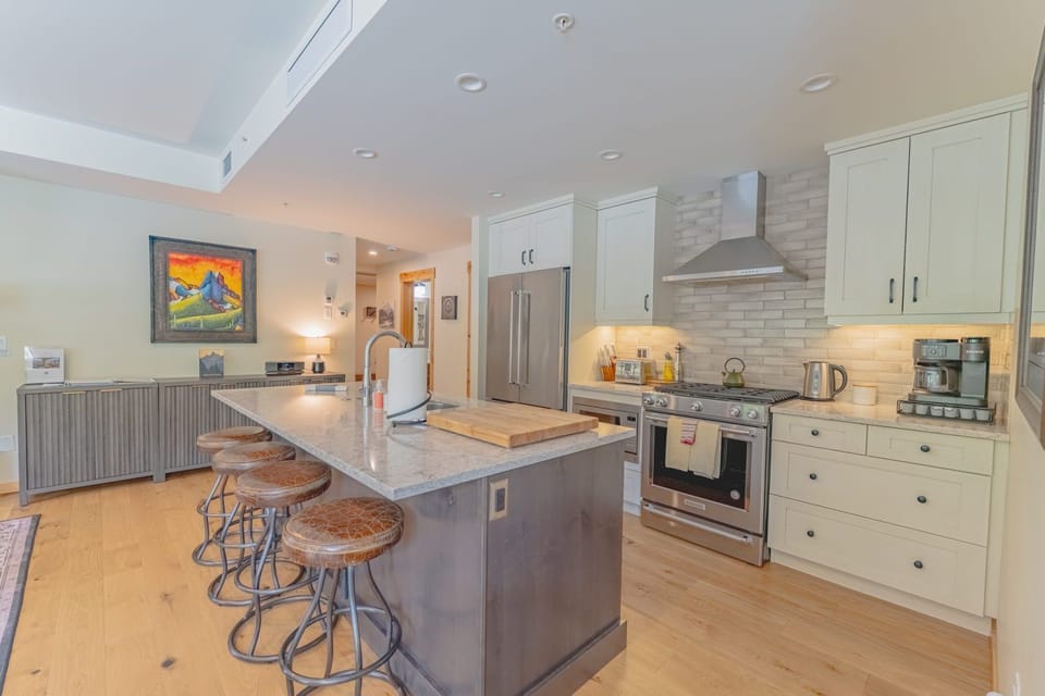 Kitchen with granite countertops, stainless steel appliances, and bar stools