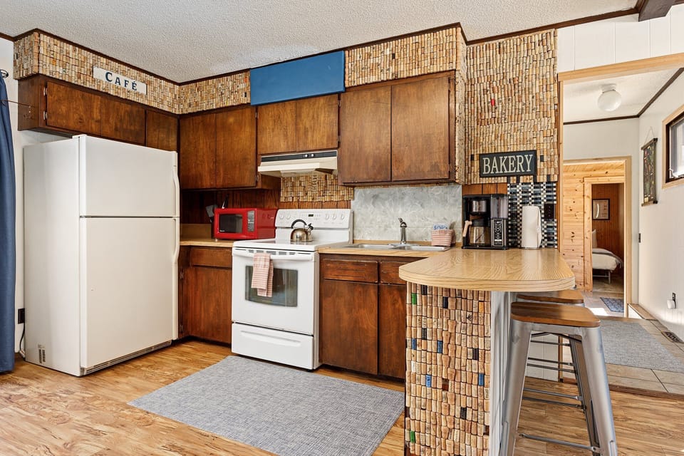 Rustic kitchen w/ wood cabinetry, open shelving & breakfast bar for laid-back meals at home.