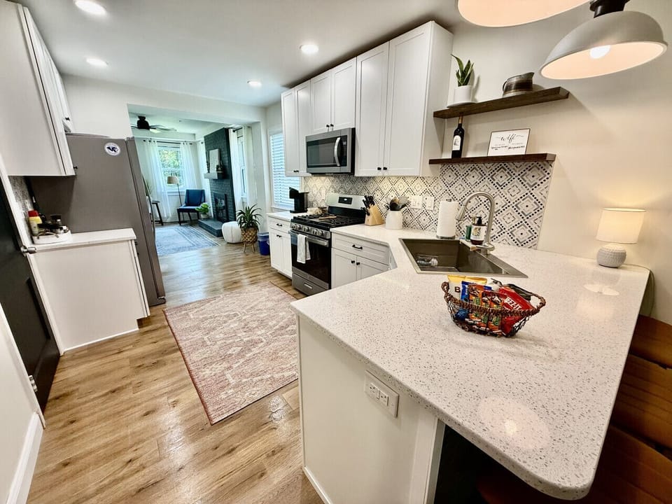 Modern kitchen with stylish backsplash, full appliances, and welcome snack basket on quartz countertop.