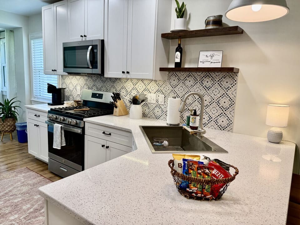Modern kitchen with stylish backsplash, full appliances, and welcome snack basket on quartz countertop.