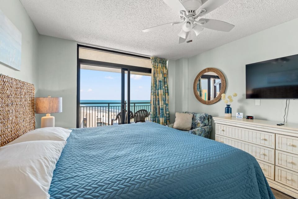 Primary bedroom with king bed, ocean views, and smart TV. Includes a private bathroom, dresser, and closet for ample storage—designed for comfort, privacy, and a relaxing coastal stay.