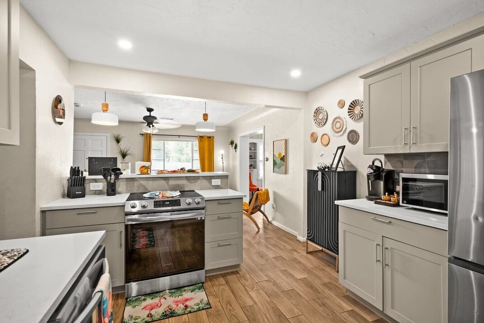 Fully equipped kitchen — stainless electric range, quartz countertops, grey shaker cabinets, and Keurig coffee bar. 4-bedroom vacation rental, St. Pete, FL.