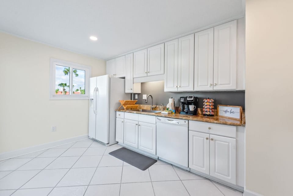 The Seabreeze Villa kitchen is bright and welcoming, featuring crisp white cabinets, marble-inspired countertops, and gold accents. Equipped with modern essentials, including a coffee station to start your mornings right. ☕✨