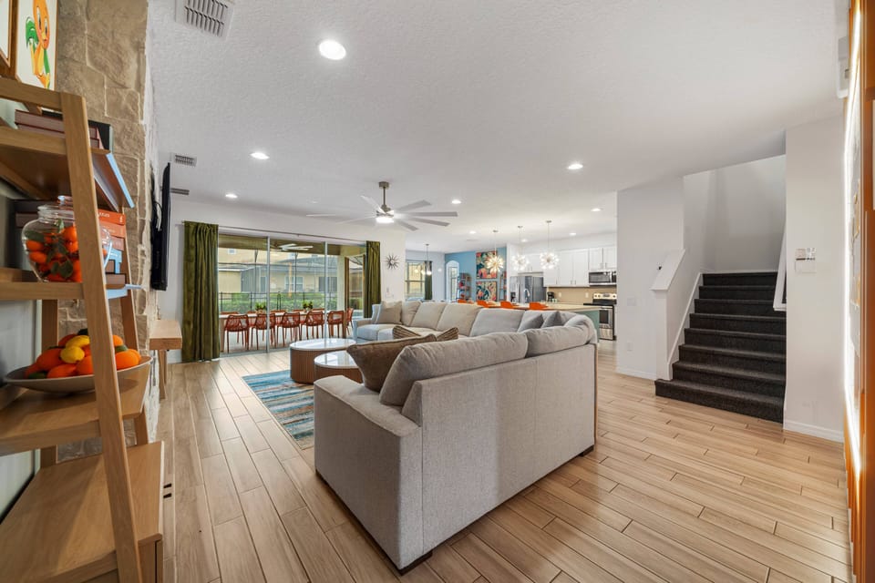 - Spacious living area with sectional sofa and open design  
- Sliding doors reveal patio dining and private pool access  
- Modern kitchen and décor create a welcoming family hub
