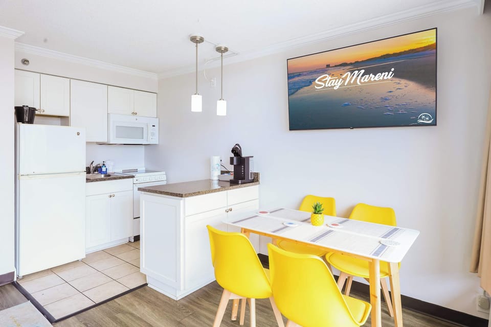 Start your mornings right in this cozy kitchen and dining nook, complete with bright seating, a coffee maker, and a smart TV to enjoy while you sip and plan your beach day.