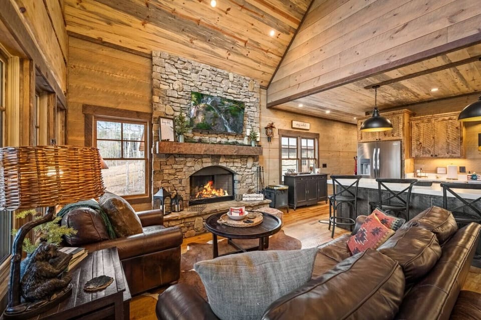 Open-concept living area with rustic charm and modern comforts. Enjoy fireside lounging, cooking in the fully equipped kitchen, or watching a movie on the smart TV.
