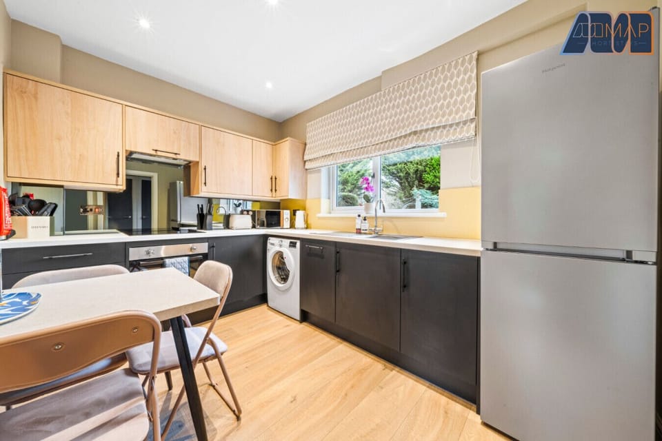 A beautifully designed kitchen with a modern touch! Featuring sleek black and wood cabinetry, built-in appliances, and a cosy dining area—perfect for cooking and enjoying meals in style.