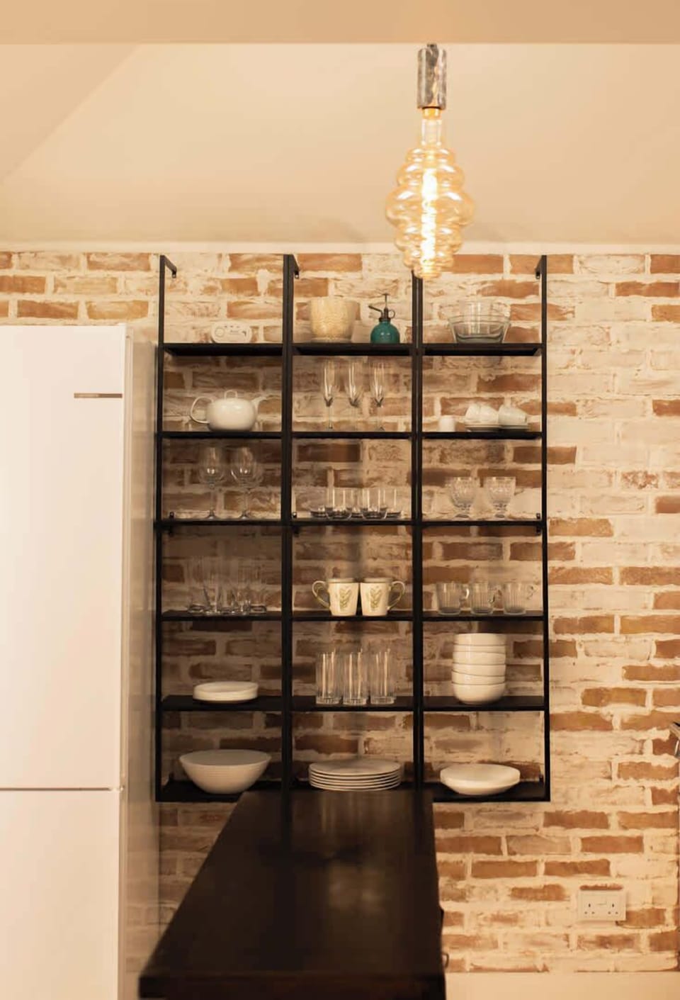 This wide shot ties it all together—black metal shelves contrast nicely with the brick, and the pendant light adds a cozy glow. The teal accent is a great touch!