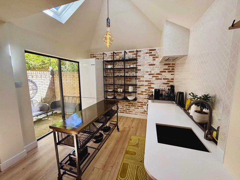 Loving the rustic-industrial vibe—exposed brick, open shelves, and sleek black accents. The glass door brings in great natural light, keeping it bright and modern.