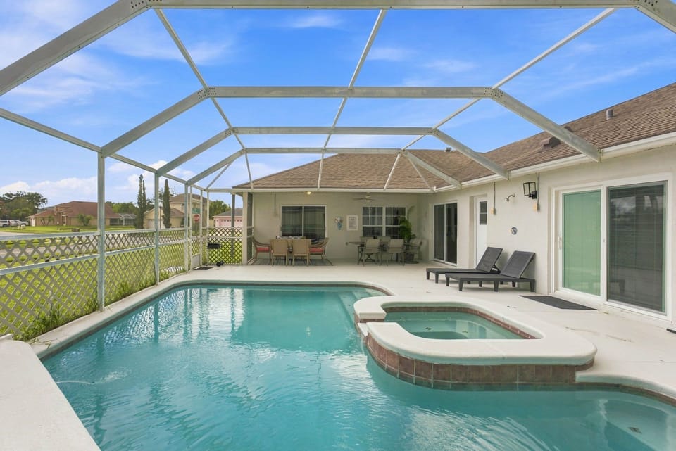 Relaxing pool area with an attached spa, lounge chairs, and a dining space for you to enjoy.