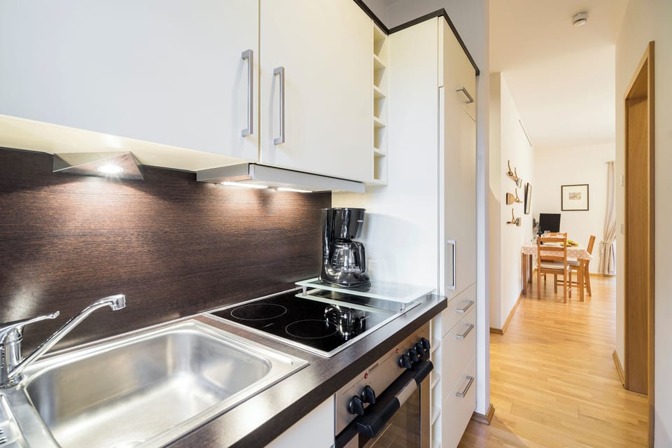 Modern kitchen with stove, sink, and coffee maker.