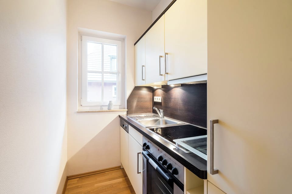 A modern kitchen with wooden countertop and windows.