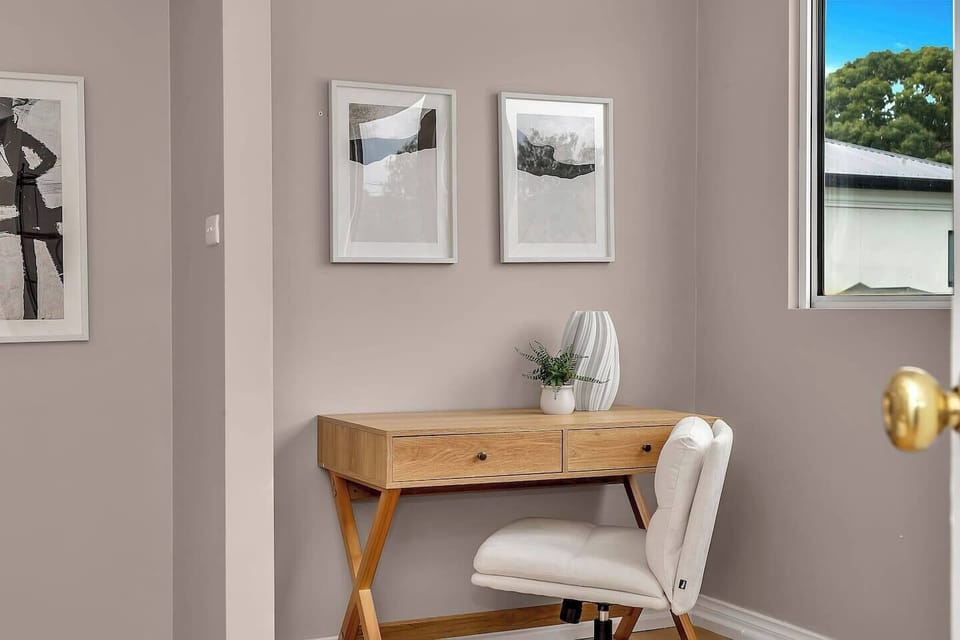 A dedicated workspace with a timber desk and upholstered chair offers a quiet corner to work or journal.
