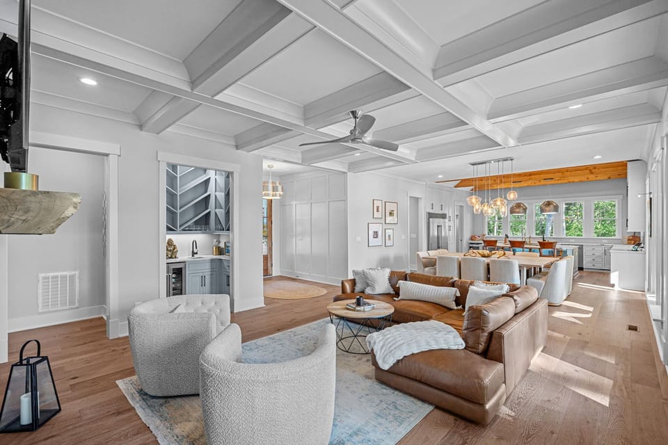 Large open concept living room with leather sectional, 2 chairs and large TV.