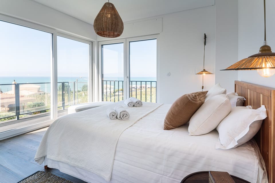 Bright bedroom with wooden bed frame and sea views — Villa Ambar, luxury holiday villa in Sintra