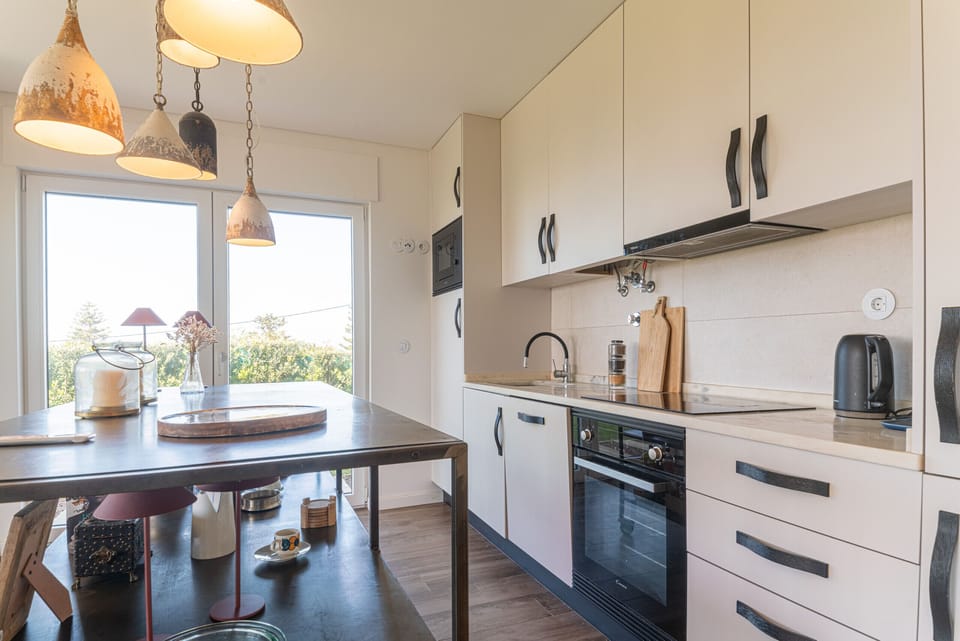 Modern white kitchen with dark island and pendant lights — Villa Ambar, luxury holiday villa in Sintra