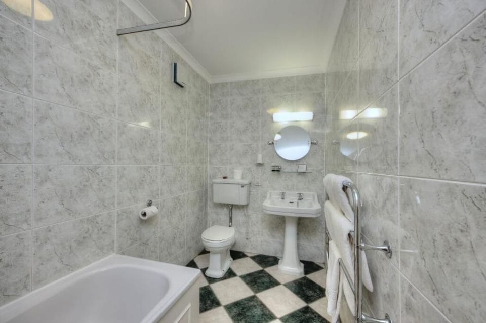 Refresh in a spotless marble-tiled bath with tub and towels.