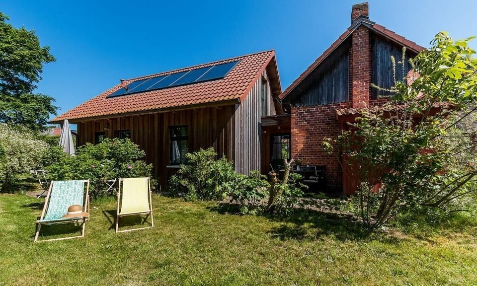 Exterior view of a house with garden and deck chairs