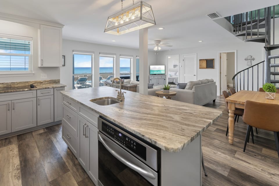 Your gourmet kitchen features granite countertops and stainless appliances, flowing seamlessly into the living area with stunning ocean views through floor-to-ceiling windows.