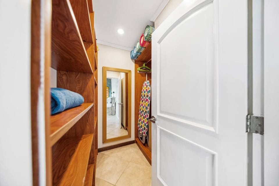 Spacious walk-in closet with shelving, beach towels, hangers, and a full-length mirror.