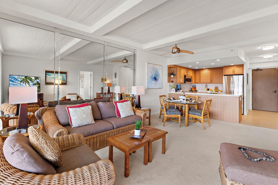 Picture yourself relaxing in this breezy open-concept space where tropical-inspired wicker seating flows into your fully equipped kitchen and dining area—perfect for unwinding after beach days.