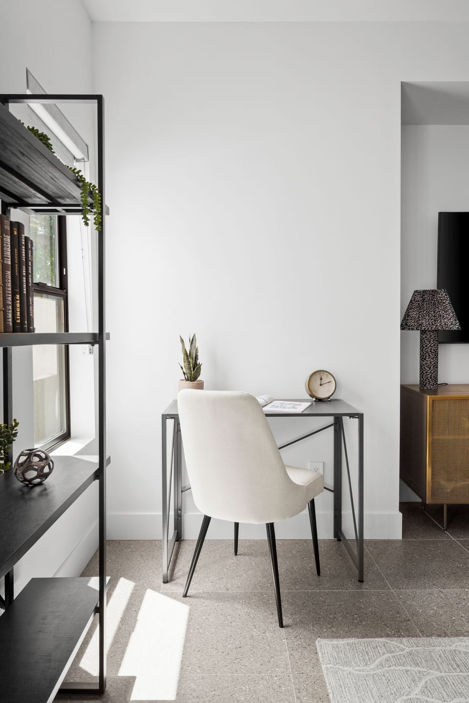 Modern desk setup with natural light and stylish shelving.