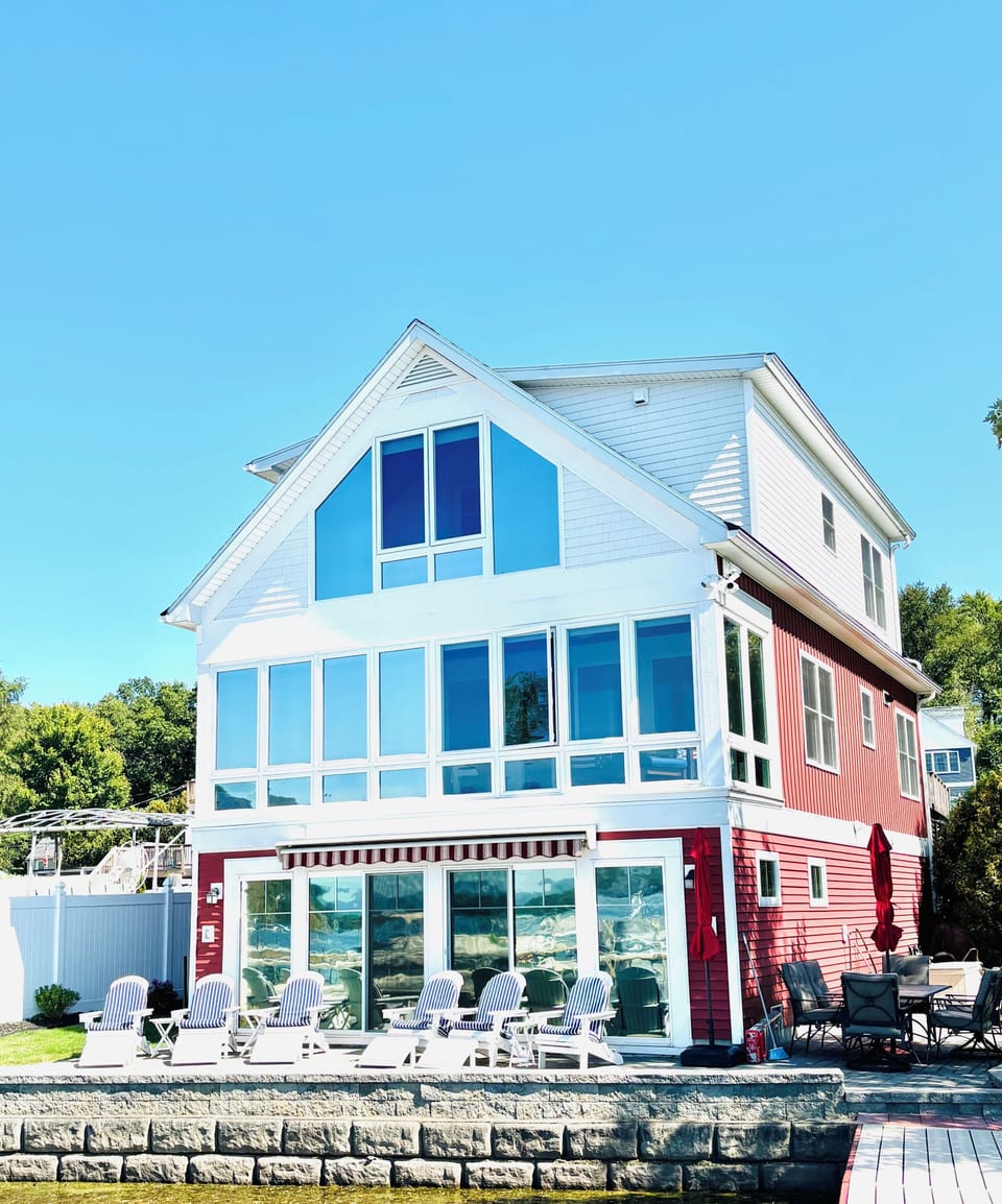 Lakeside of house - outdoor dining area and Adirondack chairs overlooking lake