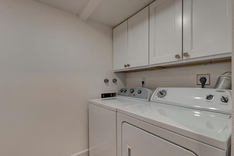 Convenient laundry room with washer, dryer, and plenty of cabinet storage.