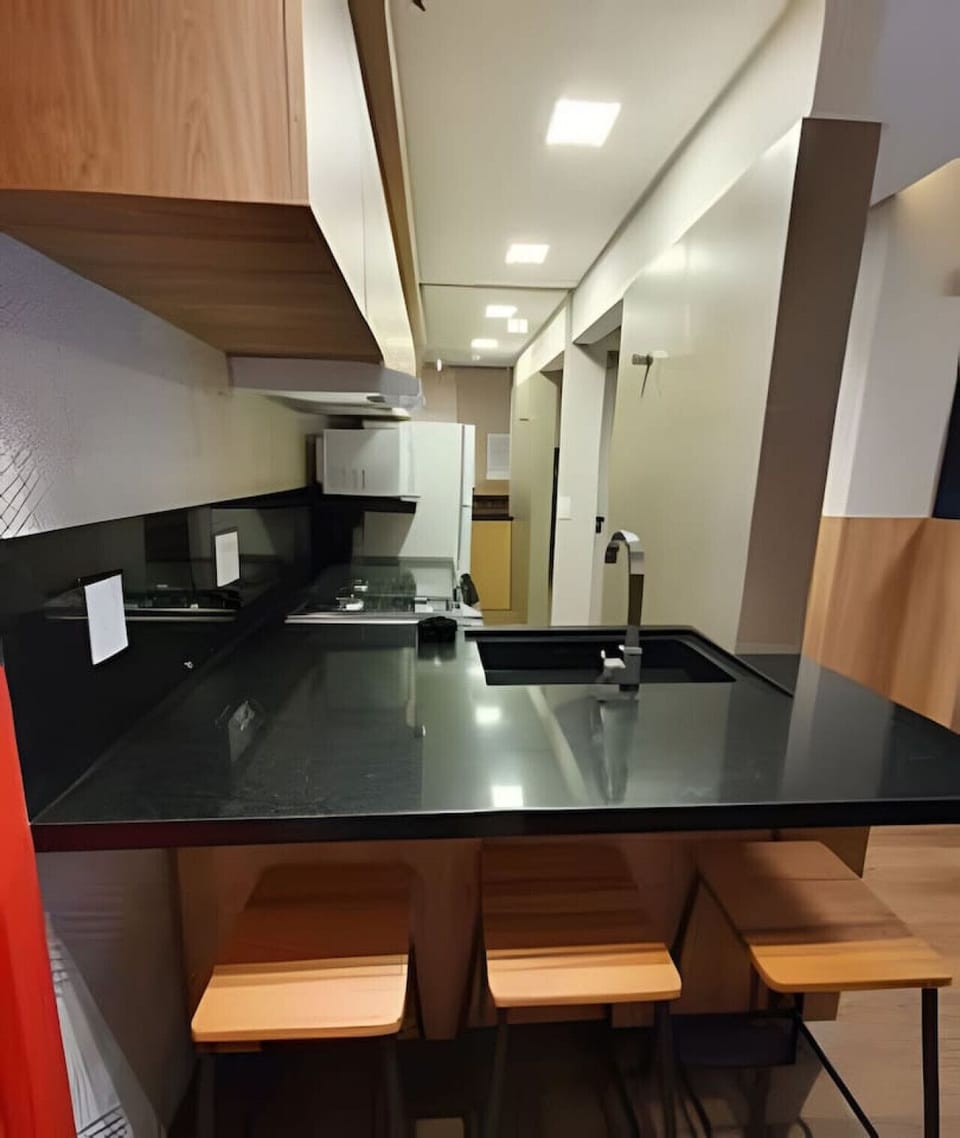 Cozinha com bancada, banquetas e equipamento completo
