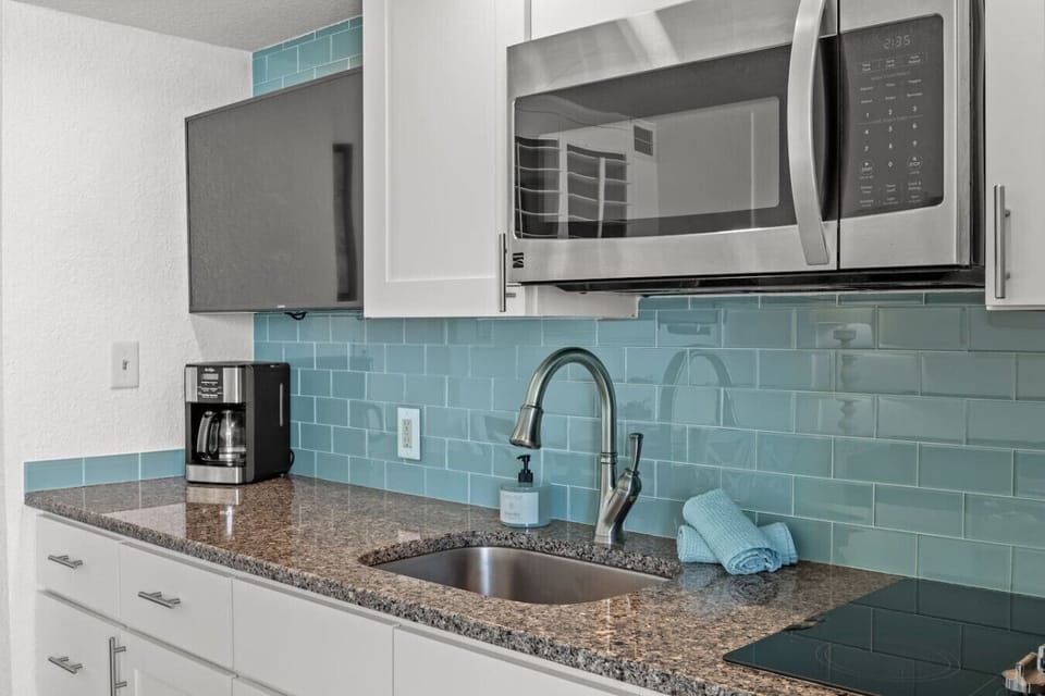Coffee maker, sink, stovetop burners, and microwave with the nautically themed kitchen.
