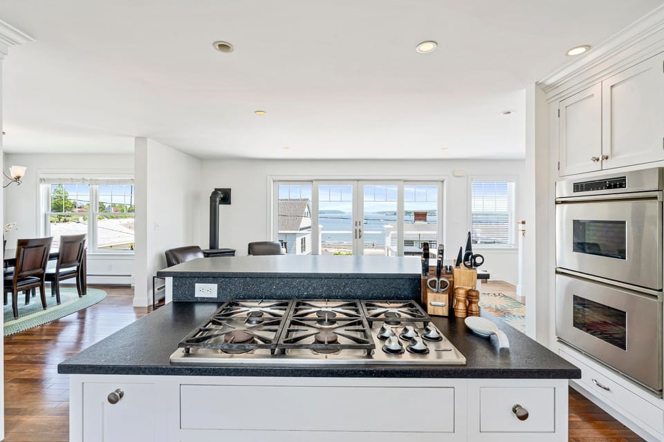 Bright kitchen with white cabinets, stainless appliances, and water view.