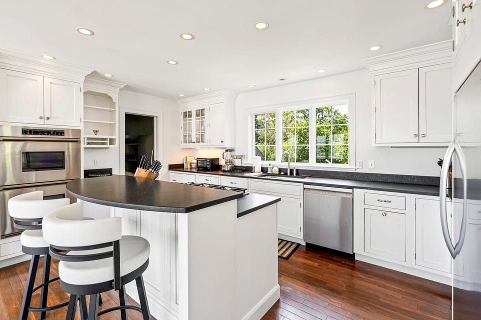 Bright kitchen with white cabinets, stainless appliances, and water view.