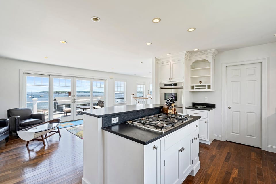 Bright kitchen with white cabinets, stainless appliances, and water view.