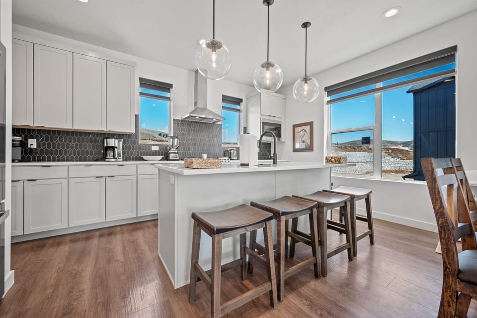 The gourmet kitchen features an island with seating for four and is equipped with brand-new stainless steel appliances, including a microwave, gas stove, and spacious refrigerator.