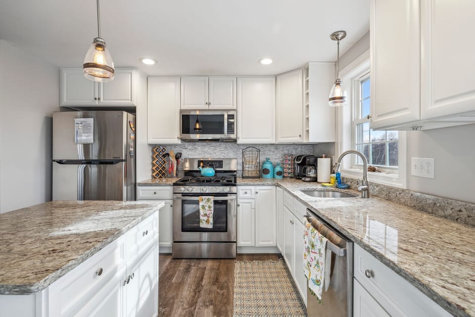 Fully equipped kitchen with updated appliances, coffee provided, and an island with seating for two.