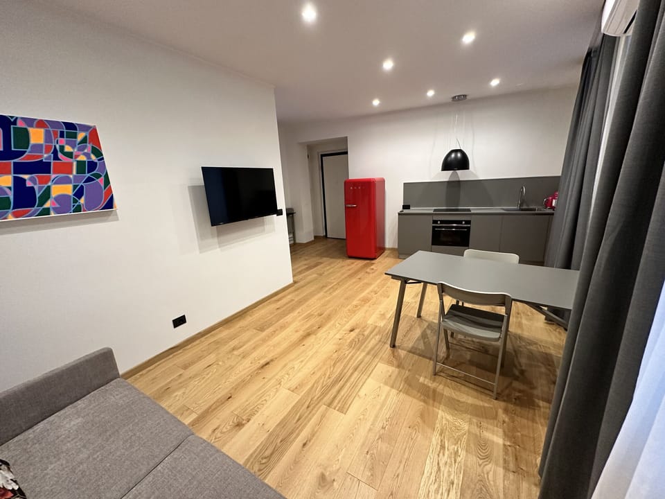 Living room with kitchenette, closet with drop-down bed, balcony on Piol street, two-seater sofa and SKY TV