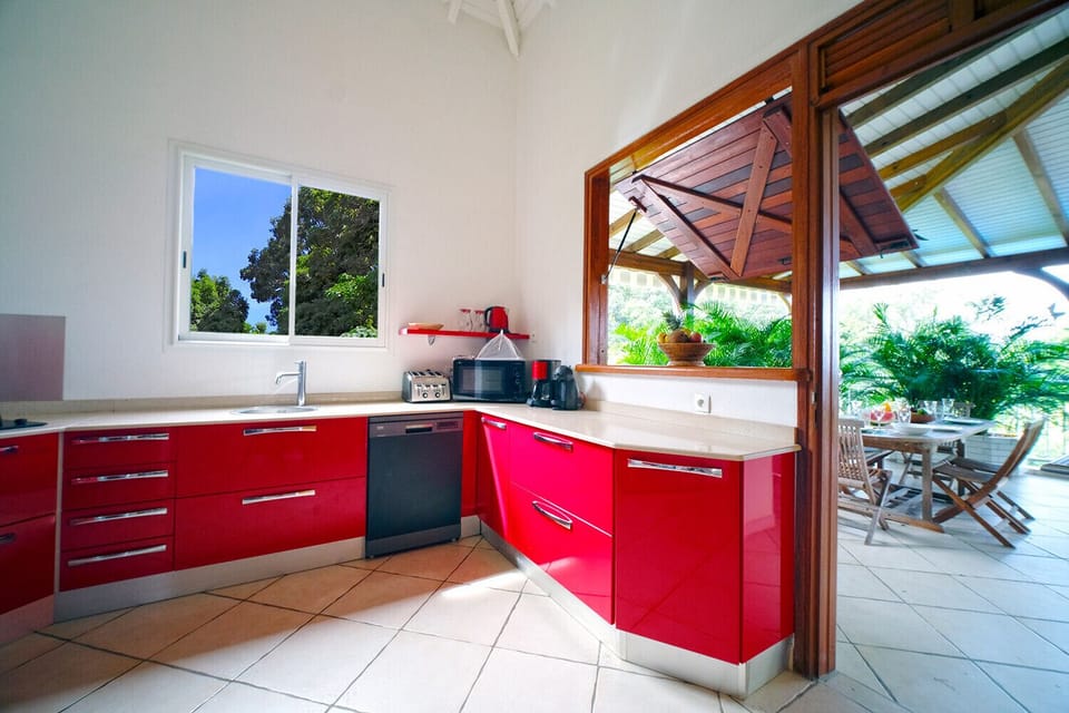 The kitchen of the villa Bwa d'Ô is complete and well equipped with a view of the mountains and the sea to prepare your favourite dishes that you will pass through a pass-through from the dining area located on the terrace. 