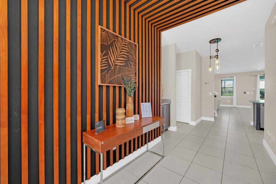 Chic entryway with striking orange striped walls and stylish console table, leading into a spacious, light-filled living