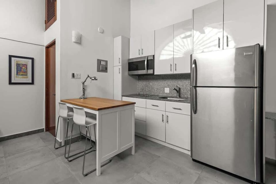 livingroom with kitchen , stainless steel fridge, air conditioner, sofabed, seats, ceiling fan, microwave,  reading lamps, cabinets