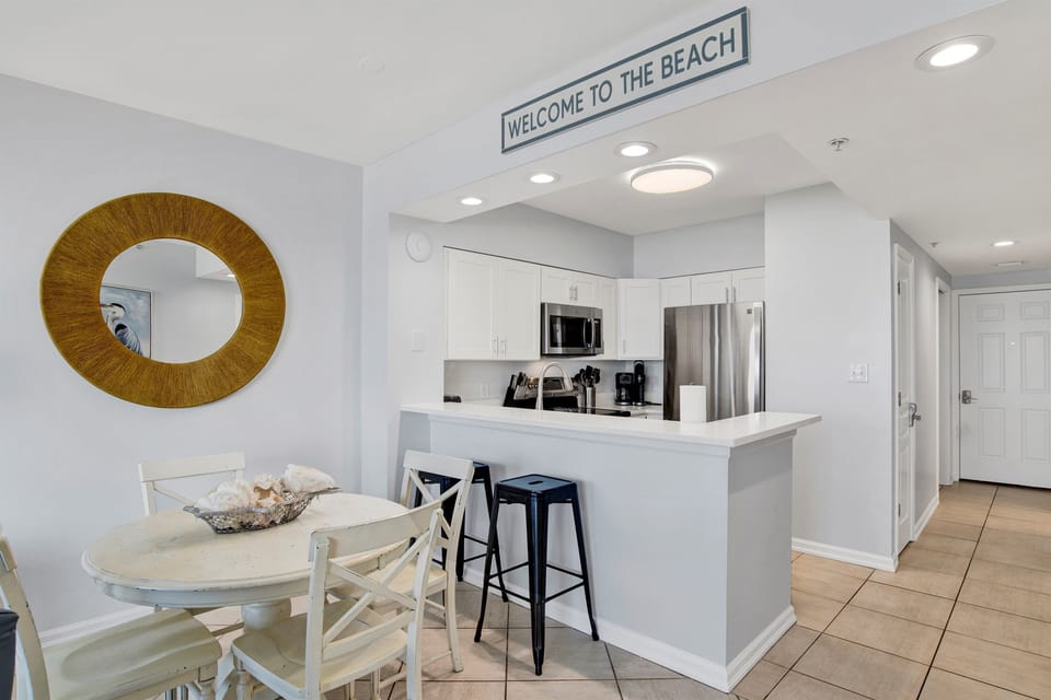Dining area with table and 4 chairs and breakfast bar seating for 2